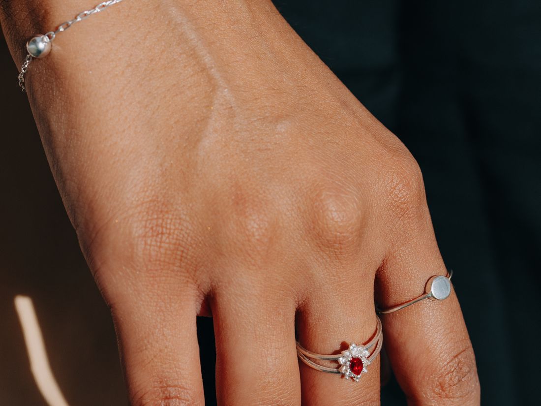 Mano con pulsera y anillos de plata a la luz del sol
