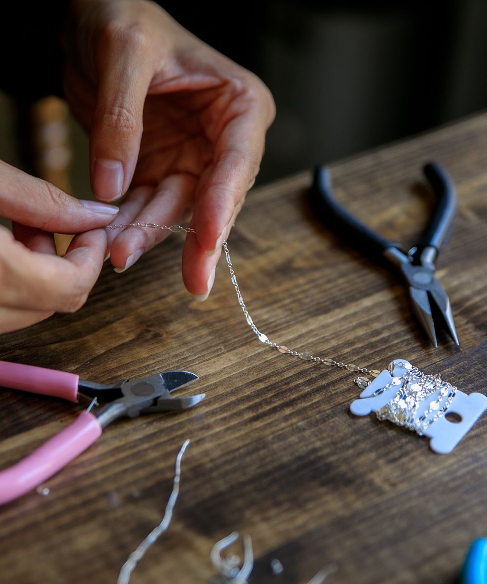 Manos de artesano dando forma a una joya de plata en el taller